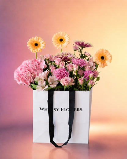 Blush Bloom Bag arrangement with pink gerberas and roses in a stylish carry bag from Whimsy Flowers Abu Dhabi.
