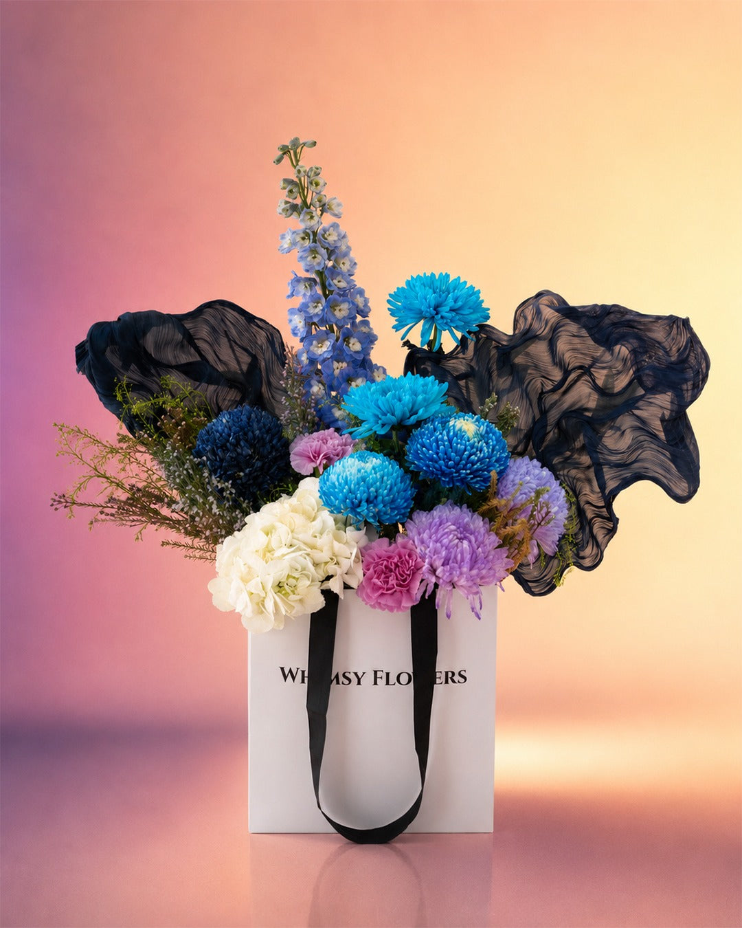Indigo Grace flower bag arrangement with blue and white blooms in a stylish carry bag from Whimsy Flowers Abu Dhabi.