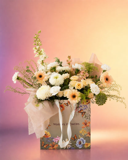 Peach Poise flower bag arrangement with soft peach and cream blooms in a stylish carry bag from Whimsy Flowers Abu Dhabi.