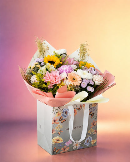 Joyful Garden flower bag arrangement with mixed pastel garden blooms in a stylish carry bag from Whimsy Flowers Abu Dhabi.