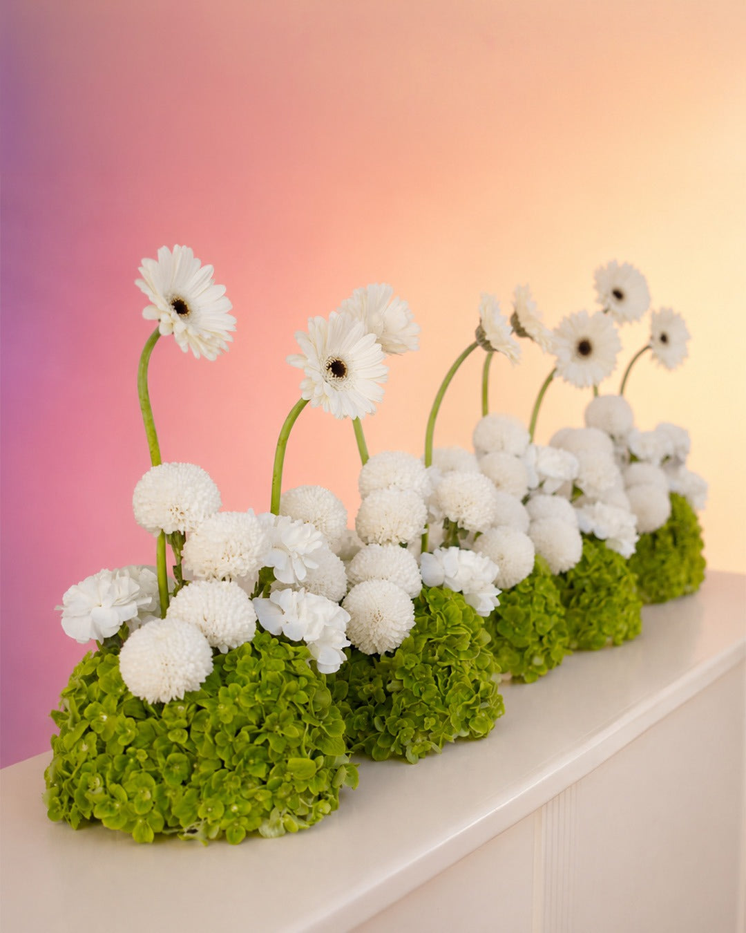 Pearl Garden flower centerpiece with elegant white blooms in a moss base from Whimsy Flowers Abu Dhabi.