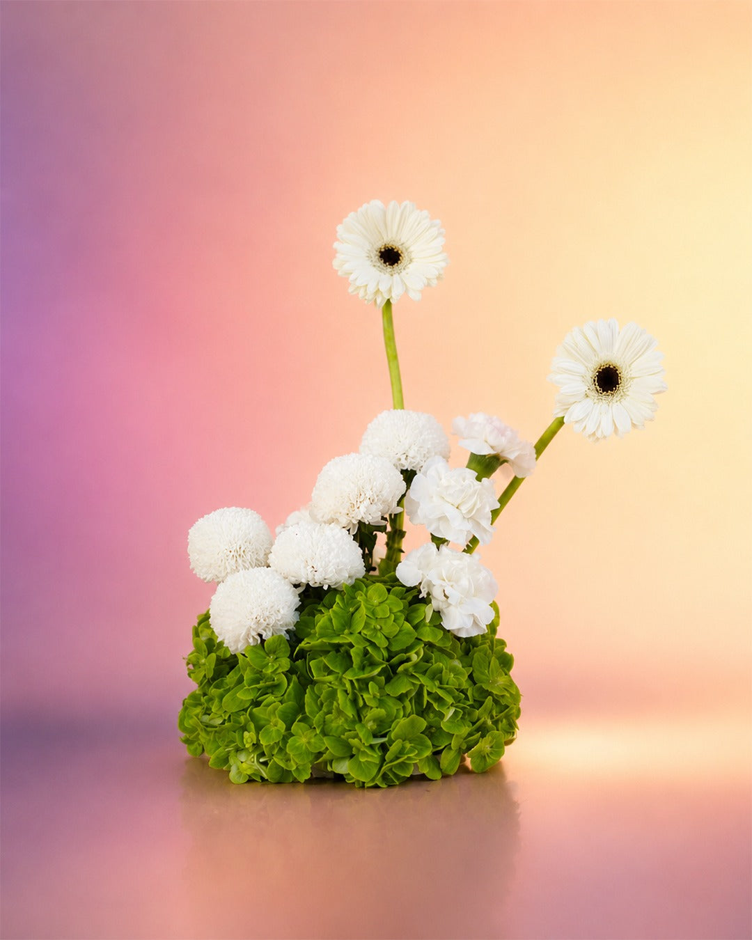 Pearl Garden flower centerpiece with elegant white blooms in a moss base from Whimsy Flowers Abu Dhabi.
