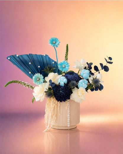 Pearls and Petals new born baby flower arrangement with blue blooms in a woven vase from Whimsy Flowers Abu Dhabi.