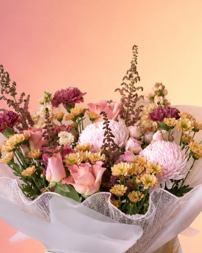 Petals and Poetry flower bouquet with pink and burgundy blooms wrapped in soft paper from Whimsy Flowers Abu Dhabi.