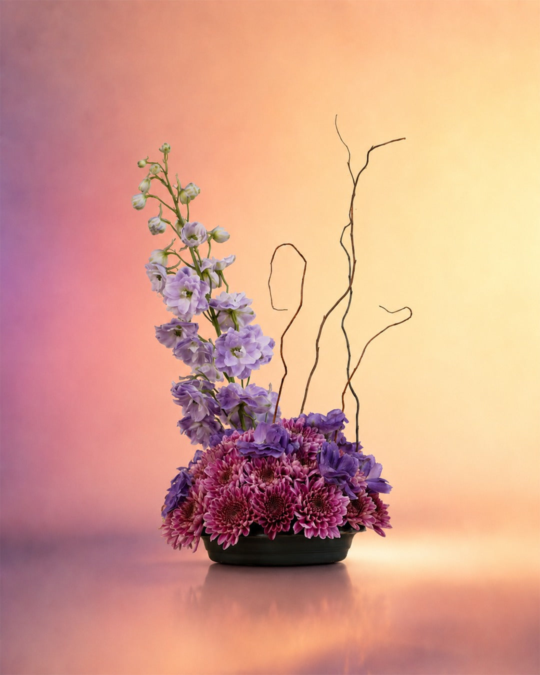 Purple Poetry flower centerpiece with dreamy purple blooms and willow in a moss base from Whimsy Flowers Abu Dhabi.