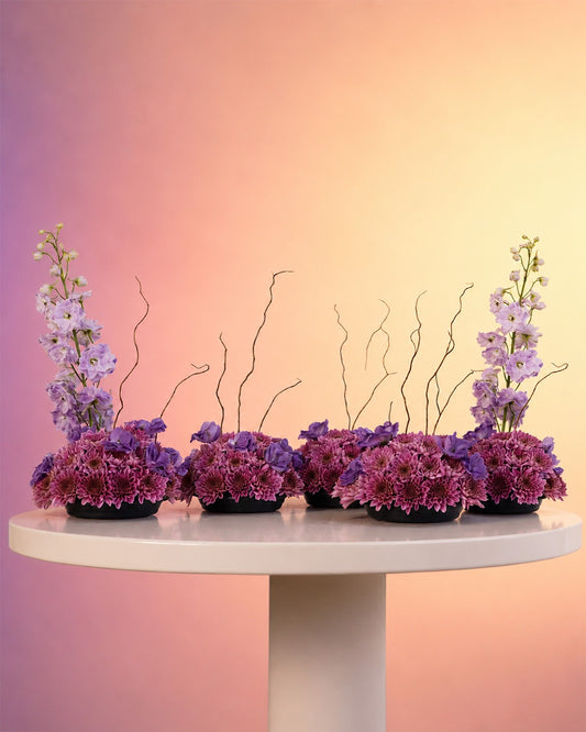 Purple Poetry flower centerpiece with dreamy purple blooms and willow in a moss base from Whimsy Flowers Abu Dhabi.