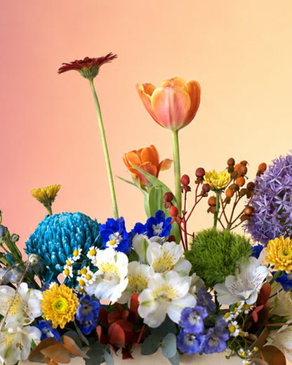 Spring Kaleidoscope flower vase arrangement with vibrant mixed spring blooms in a white vase from Whimsy Flowers Abu Dhabi.