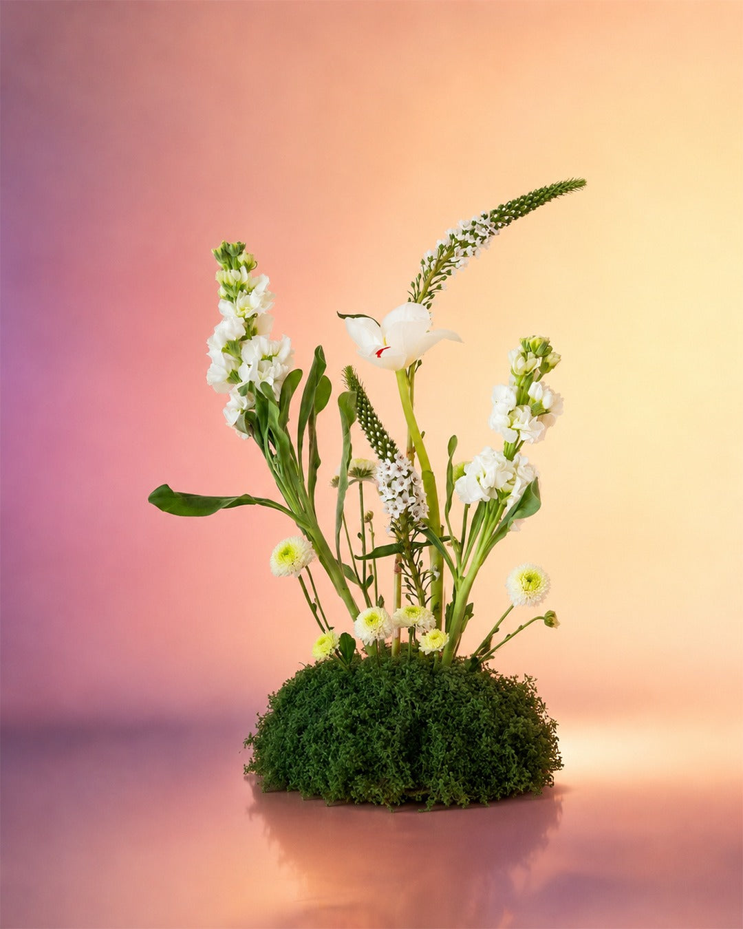 Tranquil Garden flower centerpiece with delicate white blooms in a moss base from Whimsy Flowers Abu Dhabi.
